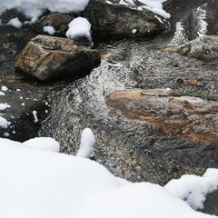Turbulent spring stream of mountain river. Water foams, breaks into splashes on stones. Power of nature, continuous movement and energy.