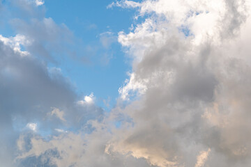 Thick cumulus clouds with pink tint at sunset. Background natural color of evening cloudscape panorama.