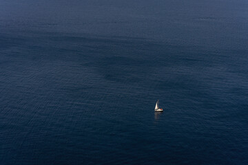 Bezkres oceanu, samotny biały żagiel na tle błękitnej wody. 