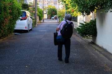 重い荷物を持って歩く年老いた女性