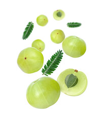 Indian gooseberry fruit (amla emblica) with green leaves flying in the air isolated on white background.
