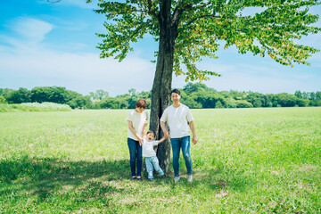 Fototapeta na wymiar 木の下で並ぶ親子3人 