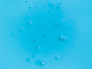 Texture of transparent antiseptic gel with air bubbles on blue background. Summer ocean imitation. Concept of skin moisturizing, prevention of virus. Liquid beauty product closeup. Backdrop, flat lay