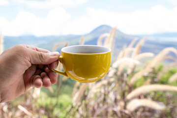 A cup of coffee is lifted in front of the view of Mount Batur.