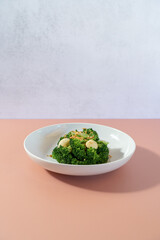 Stir-fried broccoli served on a white plate on the table.