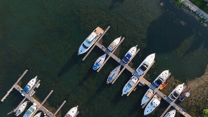 Fototapeta na wymiar A direct overhead aerial photo above a sunny dock filled with moored leisure craft and yachts are seen below at dusk.