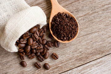 Roasted coffee bean in hemp sack and granuleatd coffe in scoop on  wood table background. Top view....