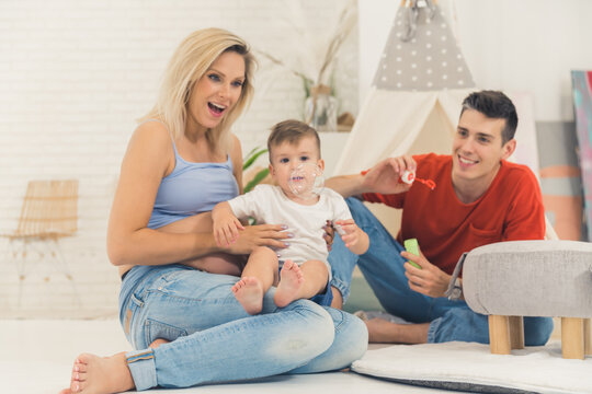 happy Caucasian family playing with soap bubbles in the living room, full shot family and well-being concept. High quality photo