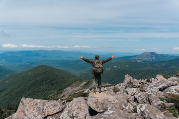 Obraz premium A man stands on top of a mountain and enjoys a beautiful mountain view. Taken on top of Mount Pidan, Russia.