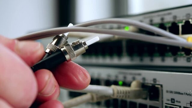Network engineer inspects fiber cable on computer switch