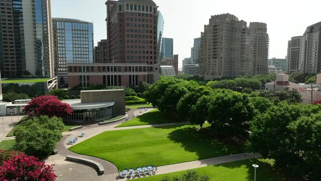 American urban city with green space park. Flowering trees and outdoor areas for relaxation and leisure among skyscraper towers. Aerial flight.