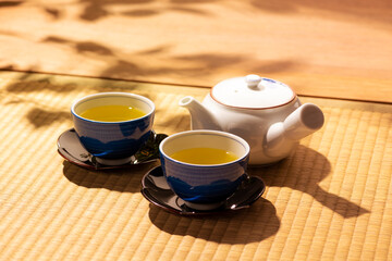 夕日があたる和室の縁側で緑茶を注ぐ