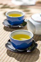 太陽の光があたる和室の縁側で緑茶を注ぐ