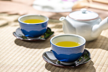 太陽の光があたる和室の縁側で緑茶を注ぐ