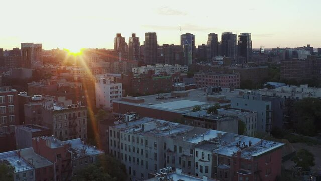 Gorgeous aerial flight over Harlem New York City towards The Bronx at sunrise with beautiful sun flare