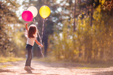 Little girl with balloons in the park.