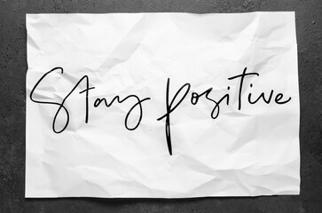 Stay positive. Lettering on crumpled white paper. Handwritten text. Inspirational quotes.