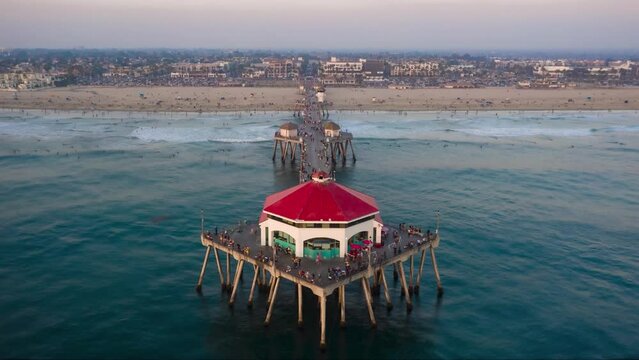 Dynamic, smoothed hyper lapse at golden hour flying up and away from the tip of Huntington Beach Pier, CA (dronie).