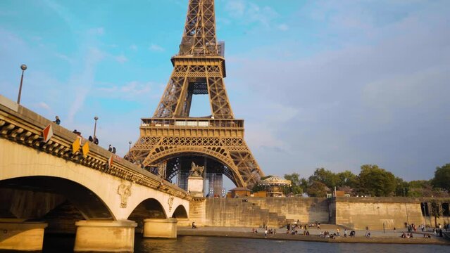 The Eiffel tower as seen from a boat emerging from under a bridge on the river Seine, Paris, France.  Sunny day, some clouds.