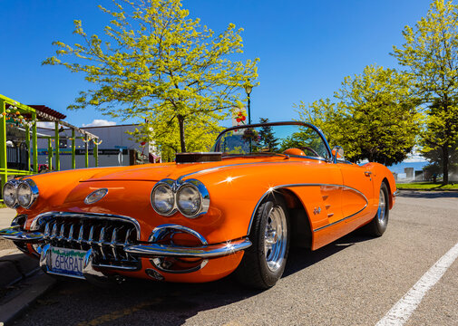 An orange 1959 Chevrolet Corvette Convertible is at summer park. Vintage Chevrolet Corvette a classic cabrio car