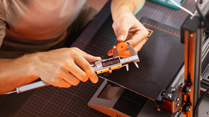 student in a workshop measures a detail printed on a 3D printer.
