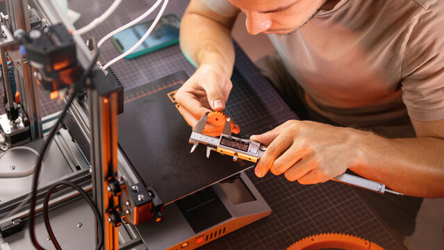 student in a workshop measures a detail printed on a 3D printer.