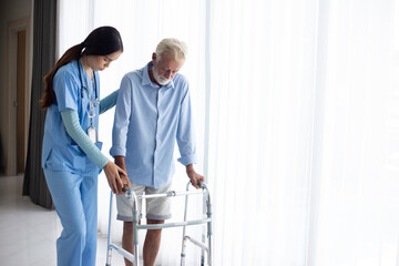 female doctor helping active senior man to walk with walker at home