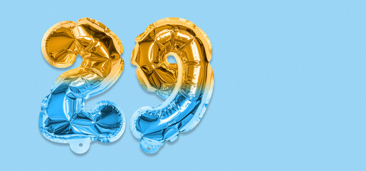 Rainbow foil balloon number, digit twenty nine on a blue background. Birthday greeting card with inscription 29. Top view. Numerical digit. Celebration event, template. Banner