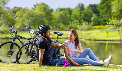 Young Asian couple resting after biking in the public park for weekend exercise activities and recreation pursuit concept
