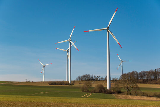 Group of wind turbines against a bright blue sky in a rural landscape, suitable as a symbolic image for renewable energies and topics related to climate change, near Höxter, Weserbergland, Germany
