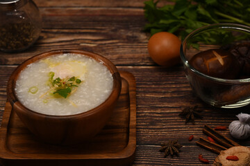 Rice porridge, rice gruel or congee with ingredients on wooden table