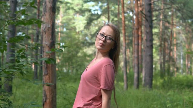 Girl with long, blonde, swaying hair turning around outdoor in summer park. Young, strong, confident woman feeling free in green woods, bright day.