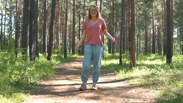 Woman enjoying summer vacation in the forest park. Smiling, laughing and happy girl with walking outdoors travel. Sunny day woods holiday journey. 