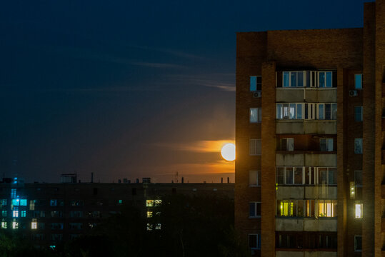 Full Supermoon On Dark Night Sky Over City