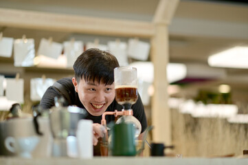 Closeup of Asian Male Barista looking at coffee in brewing machine to wait for the coffee to mix completely will get delicious coffee inside a coffee shop cafe in Thailand.
