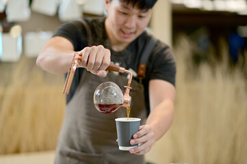 Closeup of Asian Male Barista using a coffee machine in a coffee shop to make coffee for customers to order inside a coffee shop cafe in Thailand.