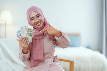 Muslim woman holding multi-currency money with smile.