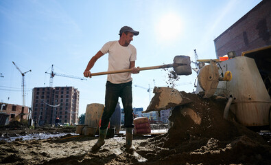 Side view of young man in white shirt working with shovel for building. Concept of process...