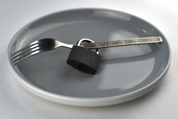 a fork with a lock on a gray plate concept diet