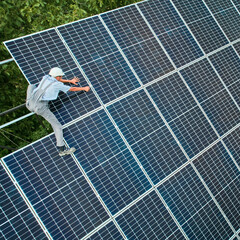 Aerial view of man technician installing photovoltaic solar panels to high steel platform. Concept...