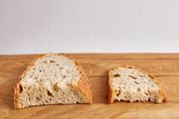 Two pieces of bread, a larger and a smaller piece on a wooden table. Food crisis. Rising prices for bread and food products.