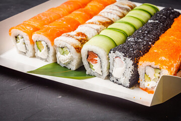 delicious sushi rolls in a delivery box on a black background © Narsil
