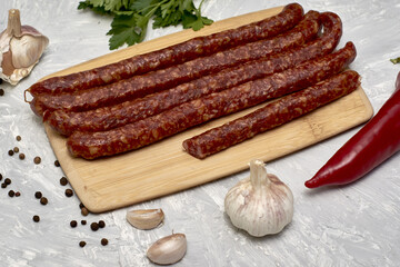 spicy smoked sausages on a cutting board next to red pepper garlic spices and herbs on the table