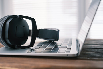 Side view of headphones with a modern thin laptop. Close up. - obrazy, fototapety, plakaty