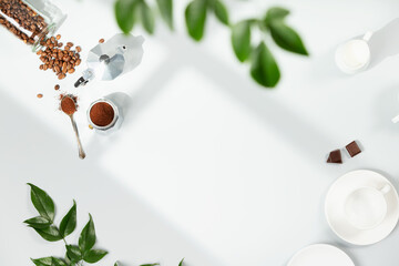 Coffee composition on light grey background, window shadow and green branches, flat lay, copy space