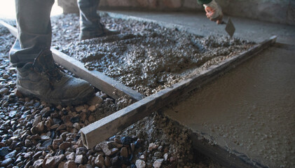 Construction worker aligns concrete screed floor.