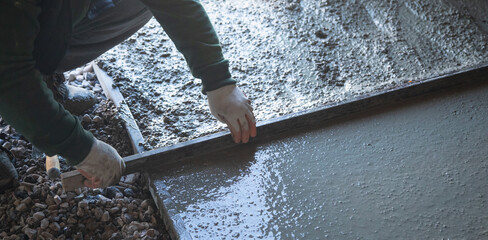 Construction worker aligns concrete screed floor.