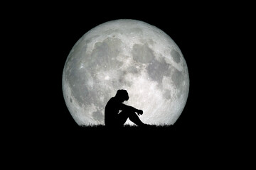 Desperate and lonely man in the background of the moon at night. Desperate, heartbreaking, and lonely concepts