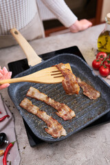 Bacon Being Cooked in grill frying pan Skillet at domestic kitchen