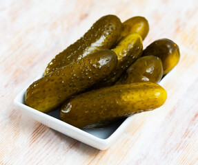 Appetizing marinated cucumbers in bowl on wooden table. Homemade pickles